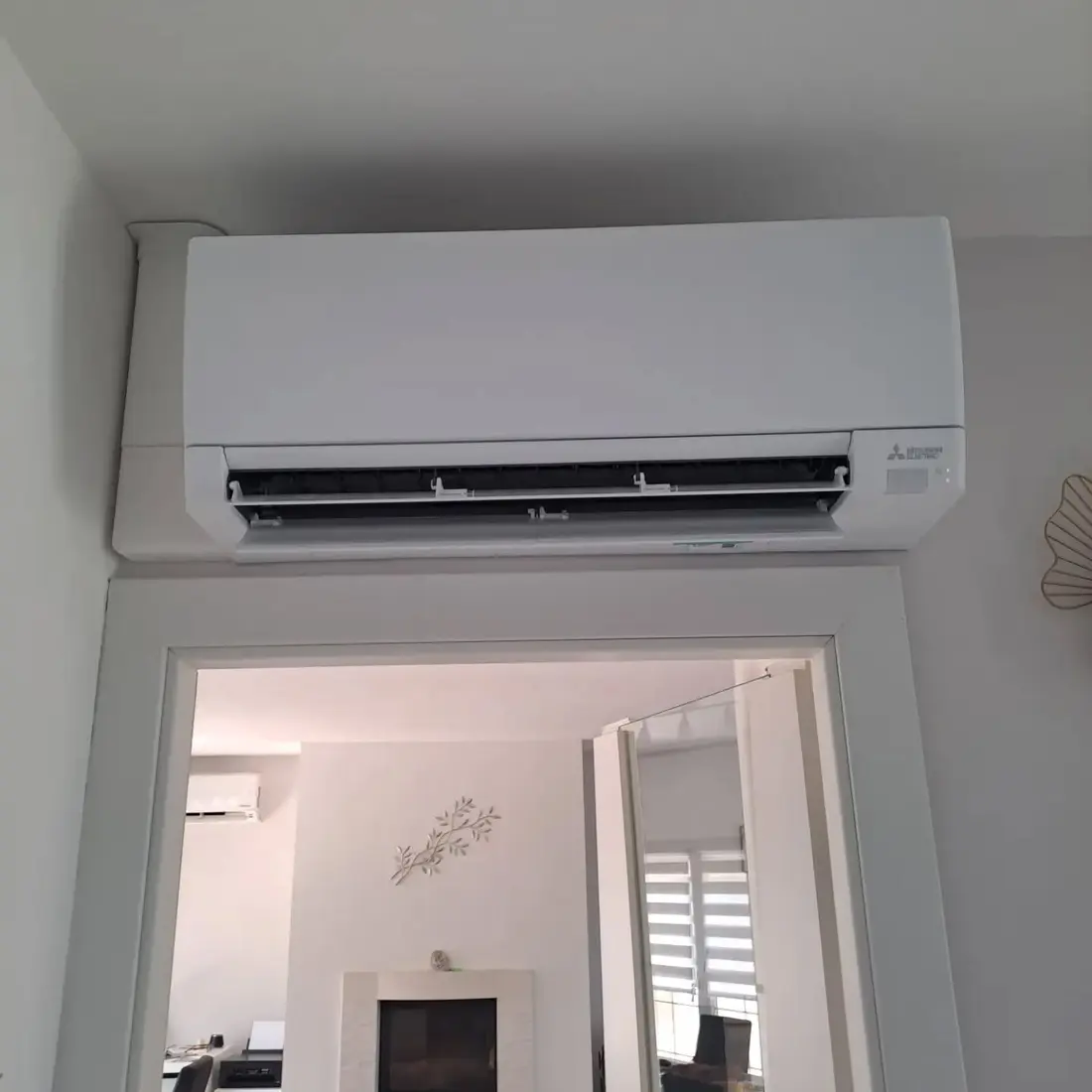 Unité murale Mitsubishi Electric installée au-dessus d'une porte, dans un intérieur clair