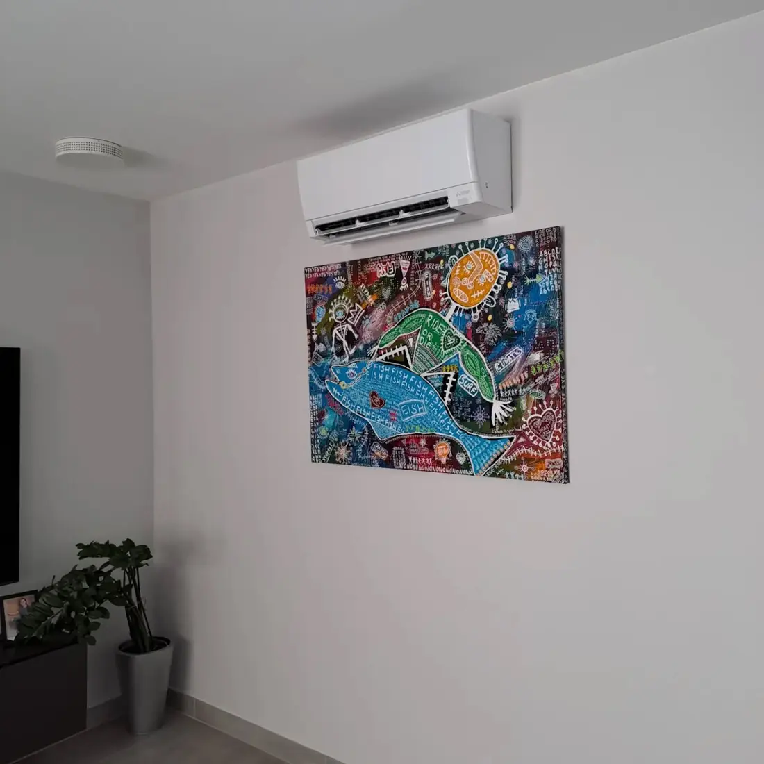 Unité murale Mitsubishi Electric dans un salon, installée au-dessus d'un tableau coloré